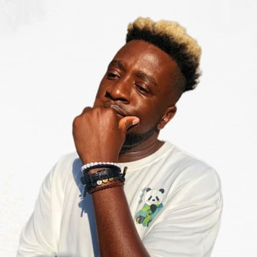 Dr Feel in a white tee and bracelets, bleached-tip hair, against a white wall